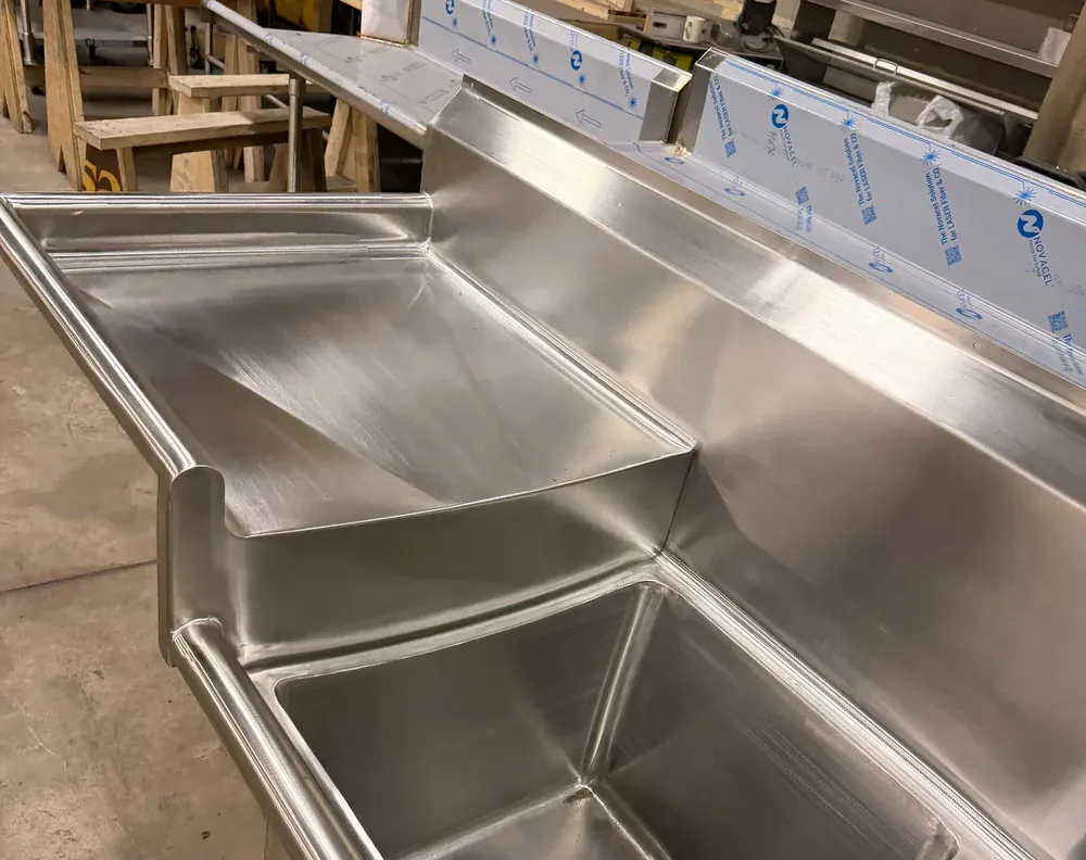 L shaped stainless steel counter with a raised rear turn-up along the wall