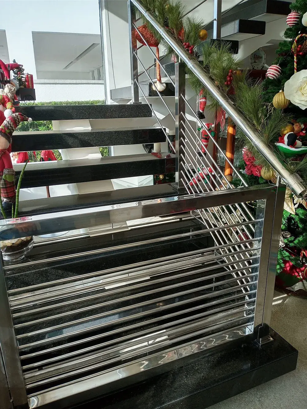 Stainless stair rail with horizontal round infill bars, the polished tubes reflecting the windows and the room