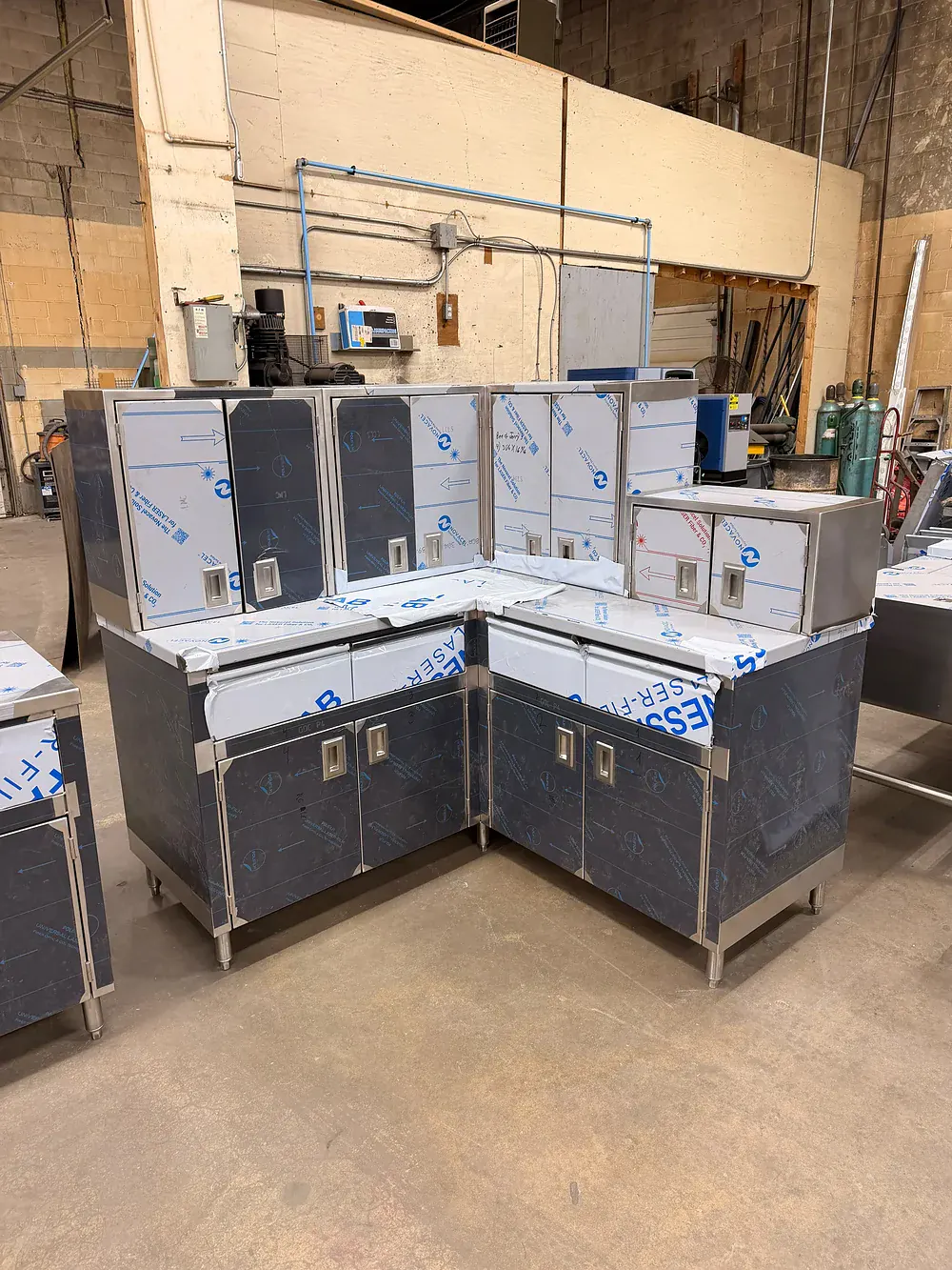 Stainless base cabinets set in an L run on site, protective film still on the doors