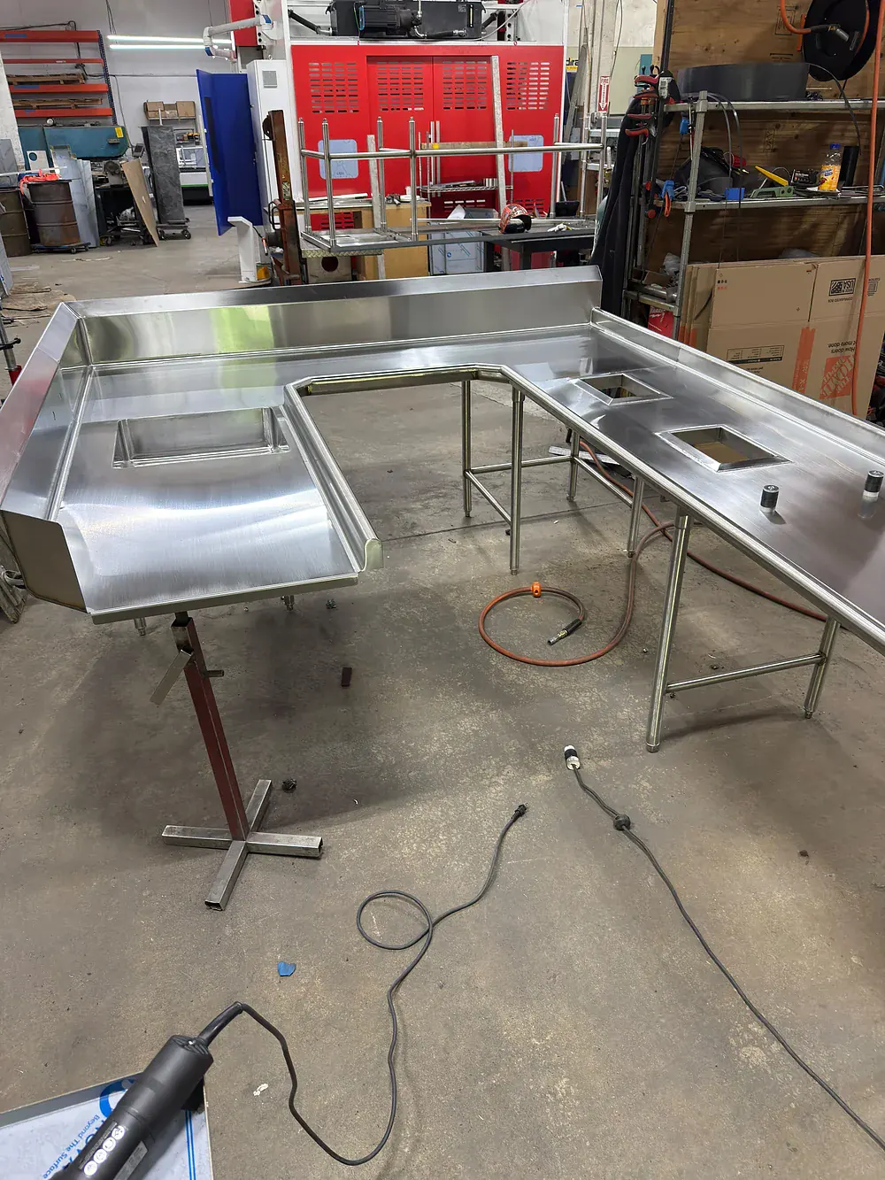 U shaped stainless dish table run with a sink well and rectangular drop in cut outs