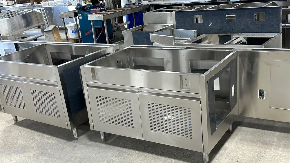Pair of stainless cooking equipment stands with perforated ventilation panels and adjustable legs